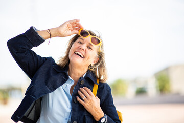 Smiling mature woman lifting sunglasses outdoors