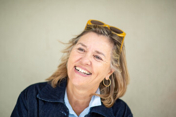 Close-up portrait of smiling older woman with yellow sunglasses