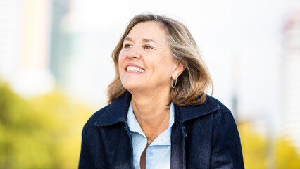 Mature woman smiling and looking away outdoors in city park