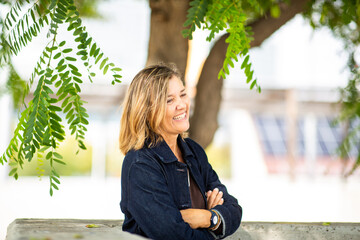 Side profile of a smiling mature woman standing under a leafy tree