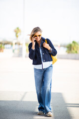 Mature woman walking outdoors while talking on smartphone