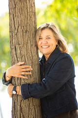 Smiling woman hugging tree with joyful expression in park