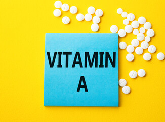 Vitamin A symbol. Concept word Vitamin A on blue note. Beautiful yellow background with pills. Medicine and Vitamin A concept. Copy space