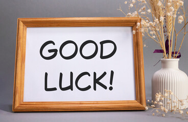 Good luck symbol. Concept words Good luck on beautiful wooden picture frame. Beautiful grey background with flower vase. Business and Good luck concept. Copy space.