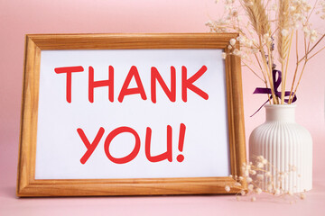 Thank you symbol. Concept words Thank you on beautiful wooden picture frame. Beautiful pink background with flower vase. Business and Thank you concept. Copy space.