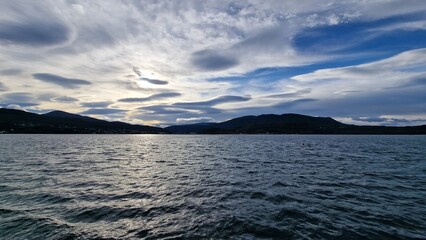 A fjord in Fauske, Norway, framed by rugged mountains and calm waters, is particularly striking in autumn. The surrounding slopes are painted in shades of gold, red, and orange as the deciduous trees 