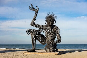 Intricate wire sculpture of a contemplative figure standing majestically by the serene ocean