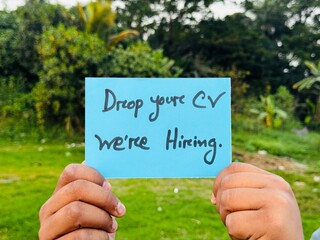 We are hiring trendy card post holding by hand, Join our team recruiting message, Drop your CV sticky note message, Vacancy here image
