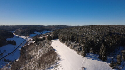 Aerial winter forest in the Black Forest with snow and rural landscape