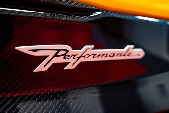 Close up shows the Performante badge on a Lamborghini Urus, with glossy carbon fiber and a yellow panel at the top edge, studio lighting, and smooth bokeh focus.
