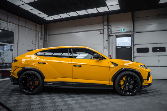 Bright yellow Lamborghini Urus Performante sits in a modern detailing bay. Black aero accents, large black wheels with yellow calipers, Y headlights, and vents stand out.