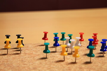 Bunte Stecknadeln stehen geordnet auf einer Korkplatte. Die kr&auml;ftigen Farben und klare Anordnung erzeugen ein lebendiges, strukturiertes Bild mit Fokus auf Organisation und Ordnung.