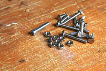 Edelstahl-Schrauben und Muttern auf verwitterter Werkbank, sichtbar Gewinde und Gebrauchsspuren, bereit f&uuml;r Montage- und Reparaturarbeiten.