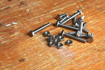 Edelstahl-Schrauben und Muttern auf verwitterter Werkbank, sichtbar Gewinde und Gebrauchsspuren, bereit f&uuml;r Montage- und Reparaturarbeiten.