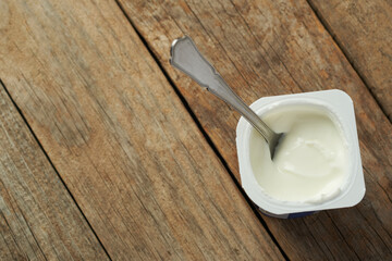Yogurt in a Container on a Wooden Table With a Spoon