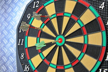 Drei Dartpfeile stecken pr&auml;zise in der Dartscheibe. Die kr&auml;ftigen Farben und der metallische Hintergrund betonen den Moment sportlicher Konzentration.