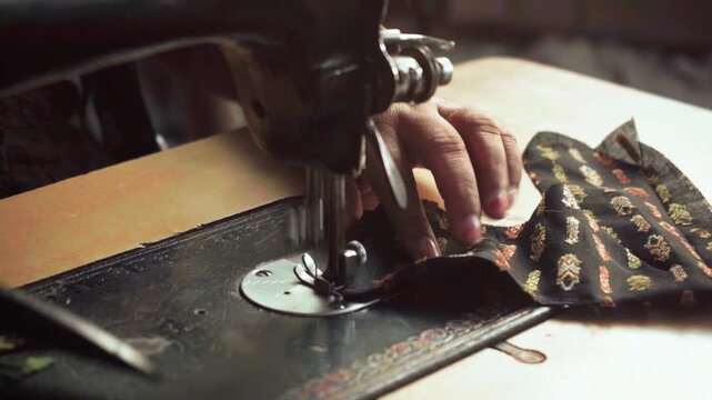 Closeup of an Indian woman hand stitching clothes on sewing machine  