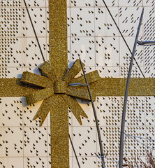 Shiny sparkling gold bow ornament outside on building wall