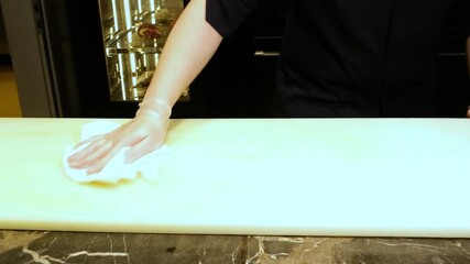 Restaurant counter being cleaned with spray cleaner and cloth after food preparation, highlighting hygiene standards and professional kitchen cleanliness practices