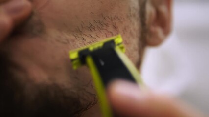 Man shaving beard with razor closeup bathroom scene young professional preparing for interview focused hand precise strokes foam traces confident morning routine personal grooming