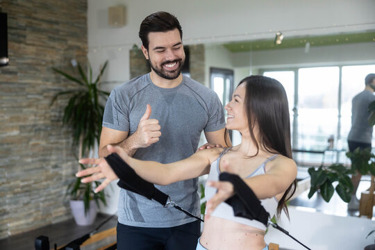 A trainer gives guidance to a client during a workout using resistance bands, showcasing proper technique and form in a well-lit session. - Powered by Adobe