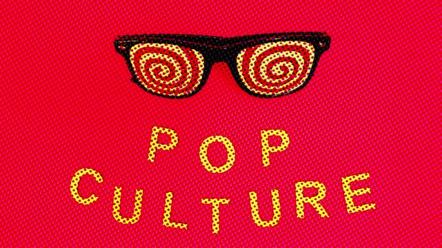 Pop culture spelled out and hypnotic glasses on a pinkish red background. Minimalist half tone.