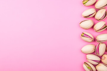 Fototapeta premium A vibrant arrangement of pistachios on a soft pink background, showcasing their unique colors and textures. Perfect for food related themes.