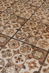 Colorful tiles with distinct designs create a decorative floor pattern in a room. The light enhances the details of each tile, showing the craftsmanship involved