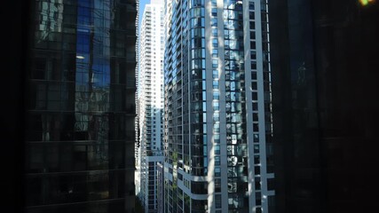 Modern skyscrapers reflecting sunlight in a dense urban landscape, captured from a high-rise window with a dynamic city view. POV view