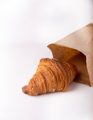 Croissant with kraft paper bag on white background, copy space