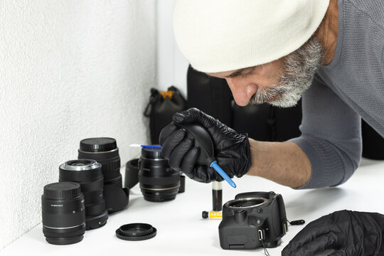 Technician wearing gloves cleaning a DSLR camera sensor with air blower. Camera maintenance, photography equipment care, studio workspace, precision and technology. - Powered by Adobe