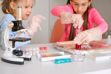 Children conduct a school experiment with mixing reagents and liquids in the classroom. Interests in chemistry and sciences