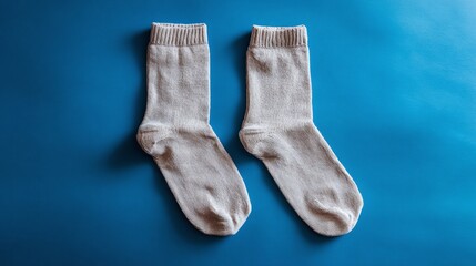 Pair of cozy socks on a vibrant blue backdrop, perfect for staying warm. This image emphasizes comfort and simple necessities, set against a flat lay presentation.