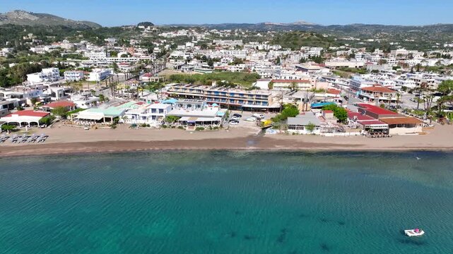 Aerial drone cinematic video of famous sandy organised beach and seaside village of Faliraki in Rhodes island, Dodecanese, Greece