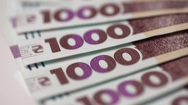 One thousand hryvnia bills stacked as background closeup. National currency of Ukraine country banknotes rotates in light space. Concept of financial support and funding with cash money