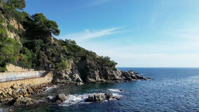 Aerial drone view, flying at the Spanish coastline with mountains and rocks, blue sea and sky, Lloret de Mar, 4K nature background	