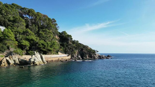 Aerial drone view, flying at the Spanish coastline with mountains and rocks, blue sea and sky, Lloret de Mar, 4K nature background	