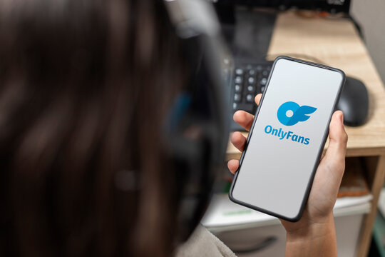 A teen holding a mobile with Onlyfans logo