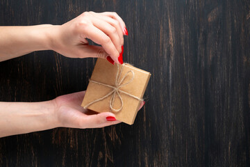 Woman opening small present on wood