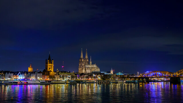 Cologne city skyline panorama at night, Rhine river with illuminated Cologne Cathedral, Great St. Martin Church and Hohenzollern Bridge, Germany