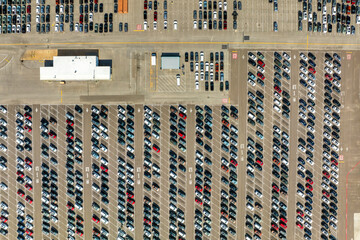 New cars stock at production factory parking lot. Vehicles parked in a row at dealer port terminal. Automotive industry. Import or export of new cars at warehouse