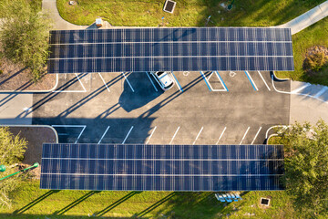 Solar panels installed as shade roof over parking area with parked cars for effective generation of clean electricity. Photovoltaic technology integrated in urban infrastructure.