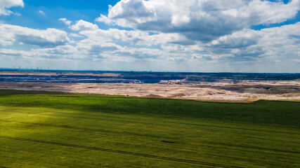 Scenic industrial landscape showing the contrast between traditional agriculture and modern energy production with wind farms and a thermal power station under a summer sky