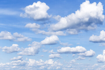 Beautiful light blue sky with many white fluffy clouds in sunlight background texture