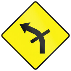 Fototapeta premium Warning road sign used in Ireland - Sharp bend to the left with a crossroads on the curve