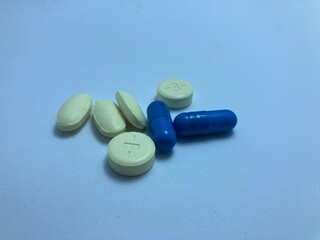 Pills and capsules of various colors and shapes arranged in a photorealistic display, representing medicine and treatment.