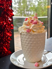 Cup of hot chocolate with whipped cream and candy canes on the table