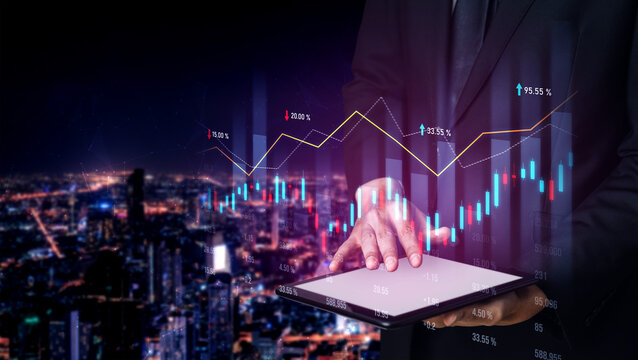 A business professional analyzes financial data on a tablet, with stock market graphs overlaying an urban night skyline, showcasing trends in investments and economic insights. Scalp - Powered by Adobe