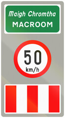 Road sign used in Ireland - Town name Macroom in Gaelic and English and speed limit