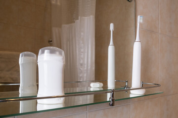Bathroom glass shelf with deodorant sticks and electric toothbrushes